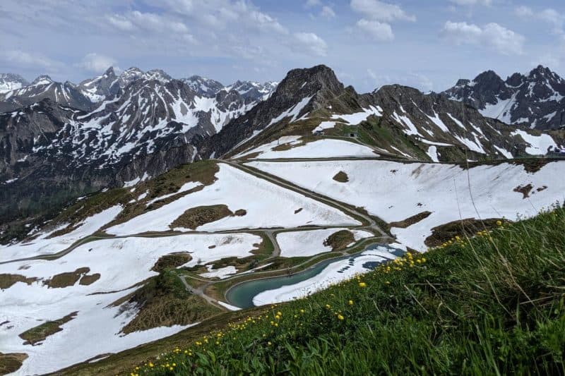 Wanderweg mit Schnee und Blumenwiese auf der Kanzelwand