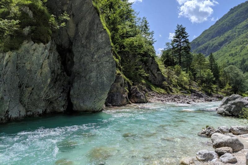 Smaragdgrünes Wasser des Soča-Flusses fließt an einem Felsen vorbei.