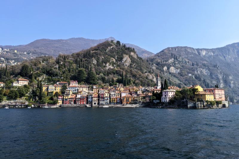 Bunte Häuser an der Uferpromenade von Varenna mit Bergen im Hintergrund