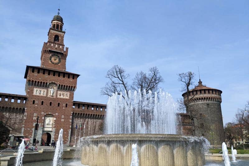 Der Hauptturm und ein Eckturm des Castello Sforzesco in Mailand hinter einem Springbrunnen