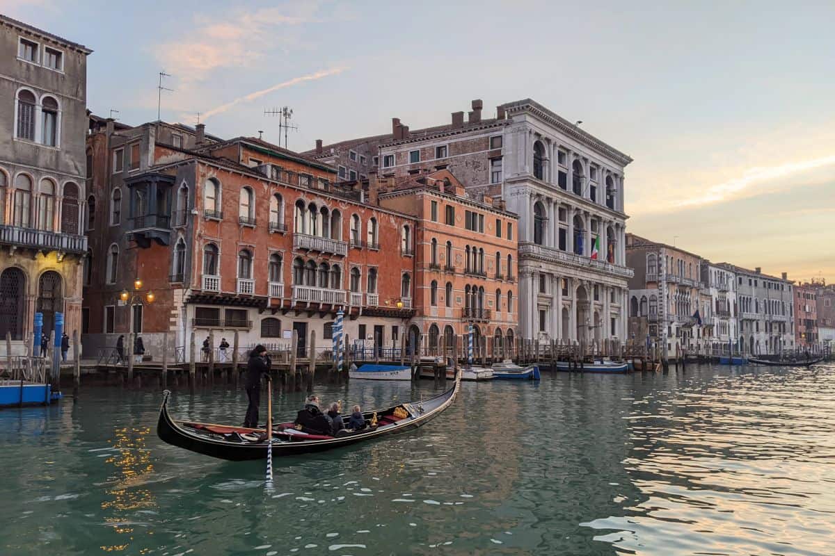 Eine Gondel vor bunten Stadtpalästen am Canal Grande in Venedig bei Sonnenuntergang