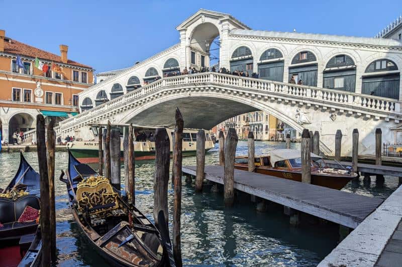 Die weiße Rialtobrücke in Venedig mit zwei Gondeln im Vordergrund