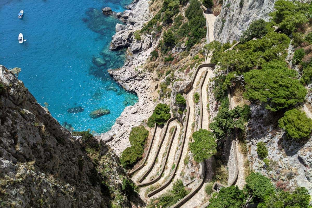 Ein geschwungener Fußweg schlängelt sich bei den Giardini di Augusto die Steilküste hinunter zu leuchtend blauem Wasser