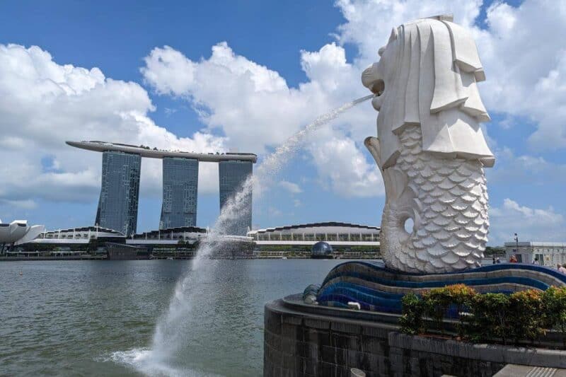 Wasserspeiende Statue des Merlion in Singapur mit den Hochhäusern des Marina Bay Sands Hotels im Hintergrund