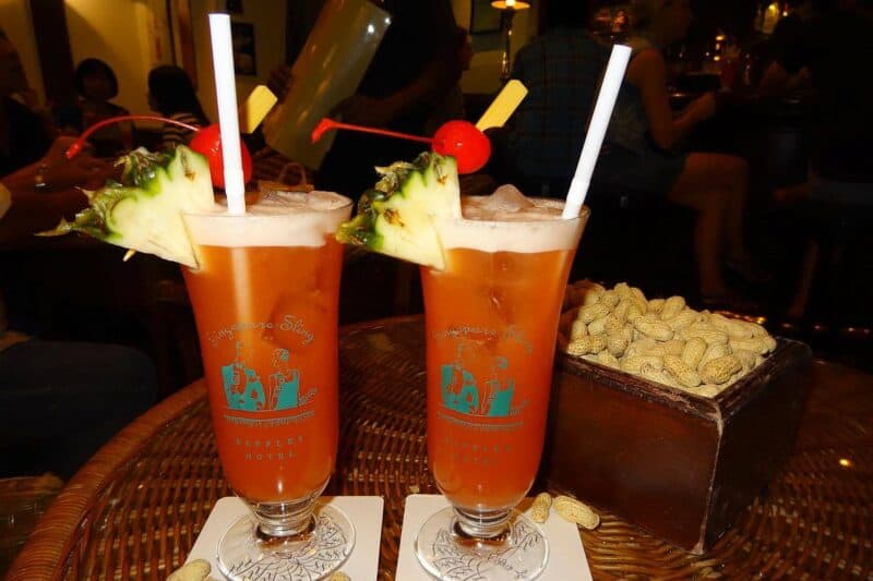 Zwei Singapore-Sling-Cocktails mit einer Schale Erdnüsse in der Long Bar in Singapur