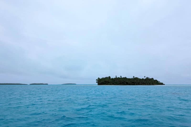 Die leuchtend blaue Lagune von Aitutaki mit mehreren Motus im Hintergrund