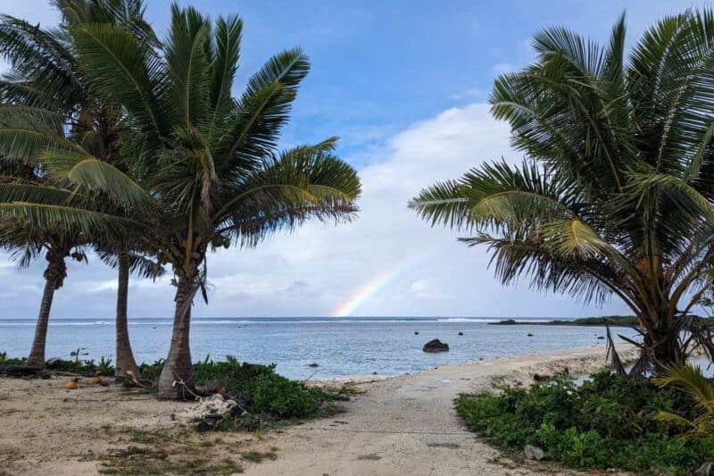 Regenbogen zwischen Palmen am Strand von Aitutaki