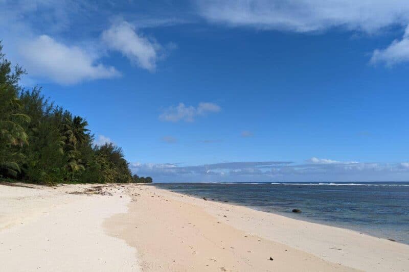 Der lange, von Palmen gesäumte Sandstrand Manuia Beach auf Rarotonga