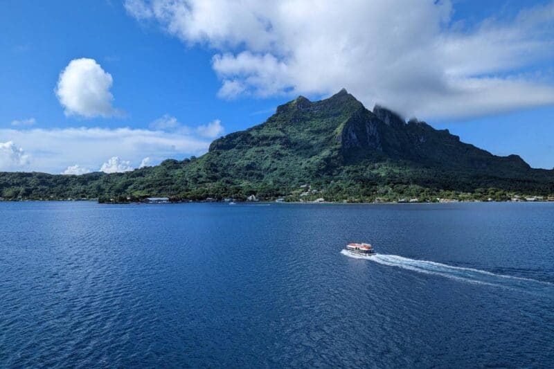 Die schroffe, spitz zulaufende Hauptinsel von Bora Bora mit einem Tenderboot im Vordergrund