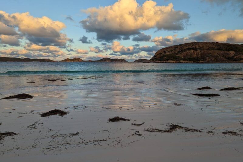 Goldene Lichtstimmung über dem weißen Sand und dem blauen Wasser des Lucky Bay Beach