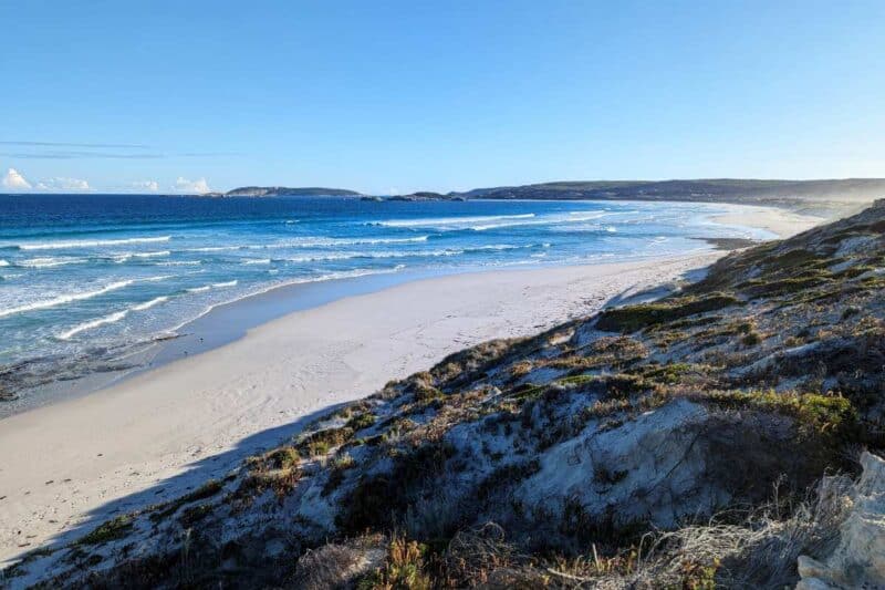 Der langgezogene Sandstrand Fourth Beach am Great Ocean Drive im goldenen Licht der Nachmittagssonne