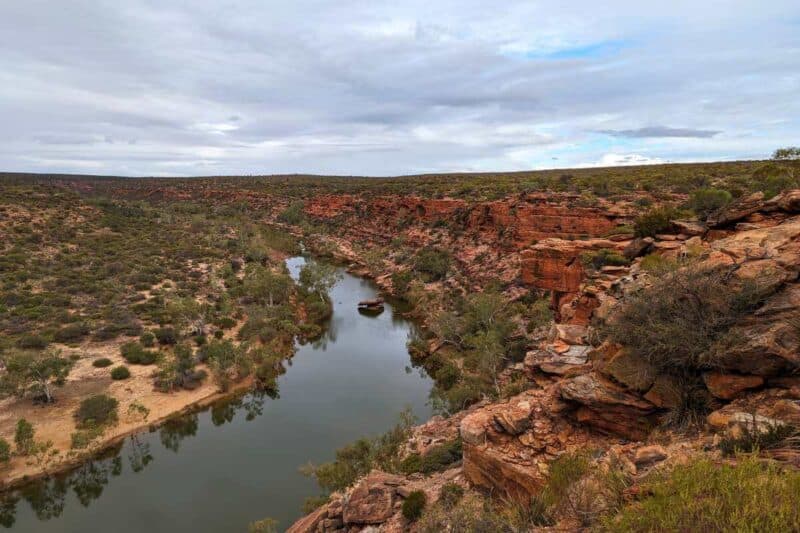 Der Murchison River zieht seine Bahn in einer langen Kurve entlang einer felsigen, fast senkrecht abfallenden Canyonwand