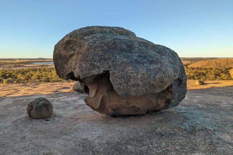 Mannshoher Findlingsbrocken vor einer weiten Aussicht über die Umgebung auf dem Hochplateau des Wave Rock