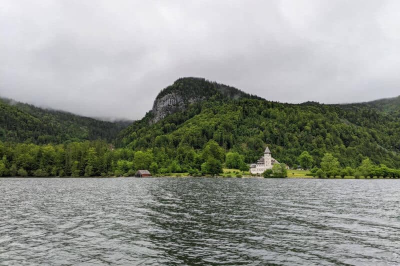 Ufer des Grundlsees im Salzkammergut mit einem Jagdschloss und Bergen im Hintergrund