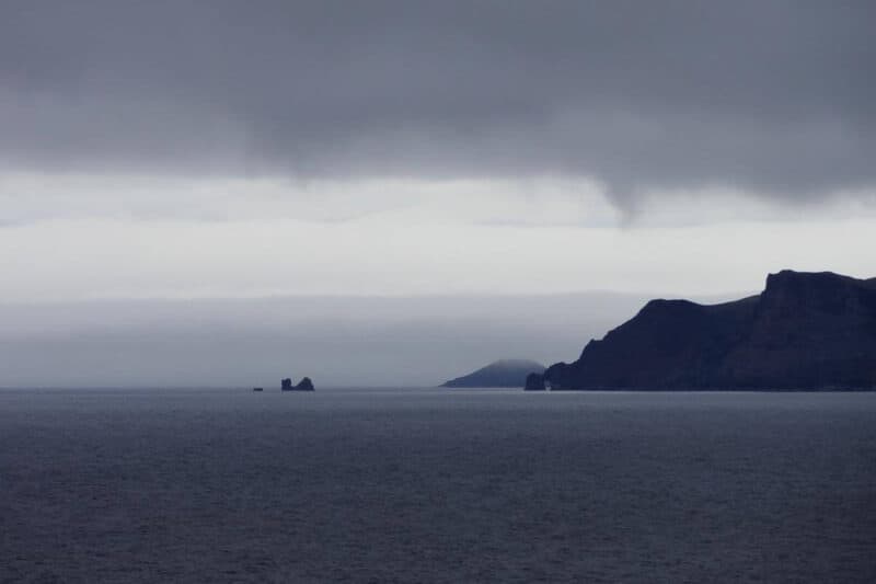 Schwarze Felsklippen im wolkenverhangenen Meer bei der Insel Jan Mayen