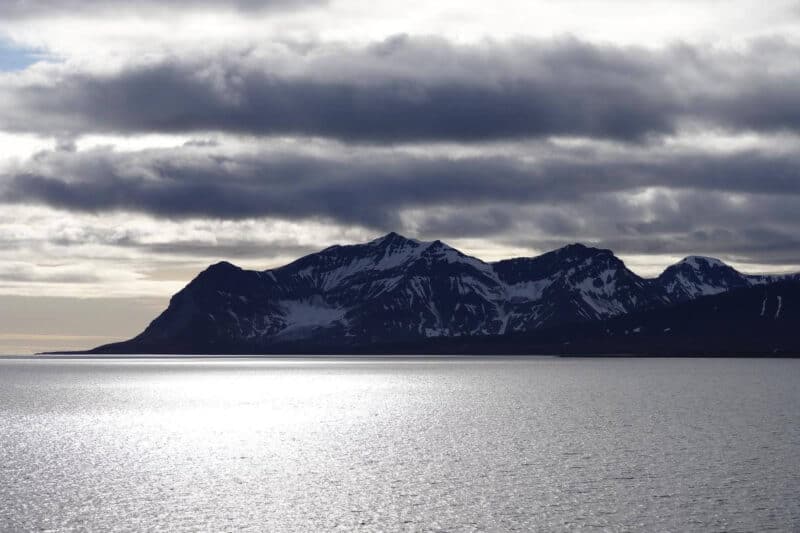 Schneebedeckte Klippen mit Sonnenreflexion im Isfjord