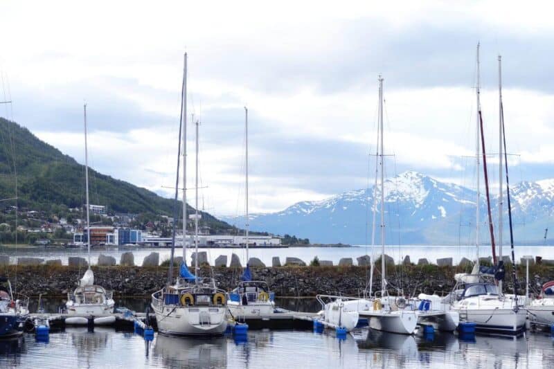 Segelboote im Hafen von Tromsø mit schneebedeckten Bergen im Hintergrund