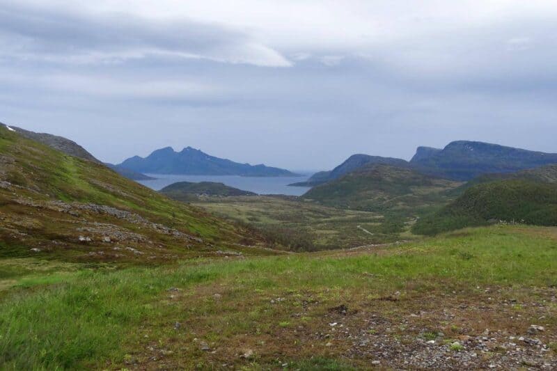 Grünbraune Landschaften mit Blick auf Berge und Bucht von der Insel Kvaløya