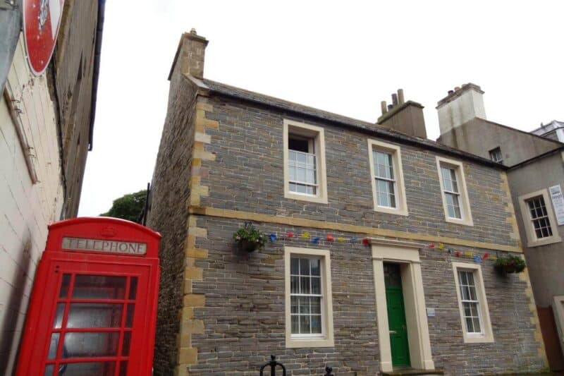 Kleines Steinhaus mit typisch roter britischer Telefonzelle im Zentrum von Kirkwall