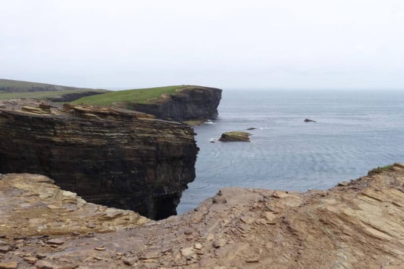 Geschichtete Felsen der Yesnaby Cliffs mit Meer im Hintergrund