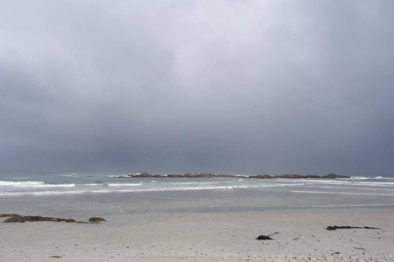 Brandung am wolkenverhangenen Sandstrand von Bloubergstrand