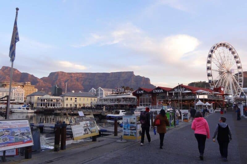 Die Hafenmauer der Victoria & Alfred Waterfront in Kapstadt mit Riesenrad und Tafelberg in der Abendsonne