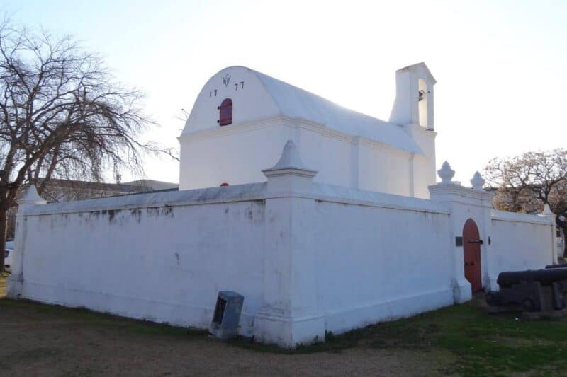Das weiße Pulverhaus mit seinem kleinen Glockenturm und einer umgebenden Mauer auf dem Platz die Braak in Stellenbosch