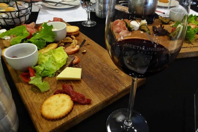 Ein Glas Rotwein und eine Brotzeitplatte bei einer Weinverkostung in der Weinregion Stellenbosch
