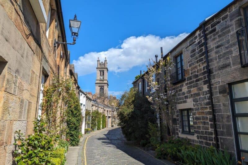 Steinerne Häuser und ein Kirchturm säumen die schmale Pflasterstraße Circus Lane in Edinburgh
