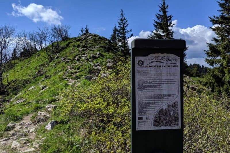 Schild mit Infos über den Nationalpark Niedere Tatra vor einem grün bewachsenen Hügel