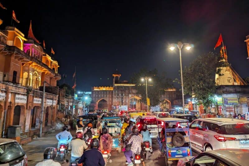 Verkehrschaos vor dem nächtlich beleuchteten Stadttor von Jaipur