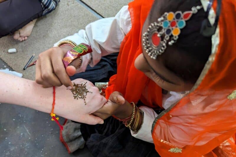 Ein indisches Mädchen malt ein Henna-Tattoo auf eine Hand